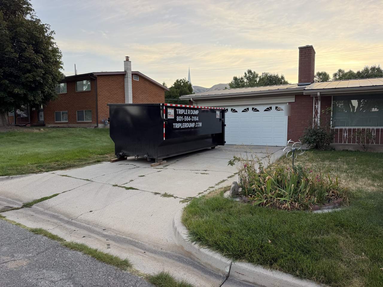 Roll-off dumpster set on wood boards on a residential driveway in Brigham City, Utah