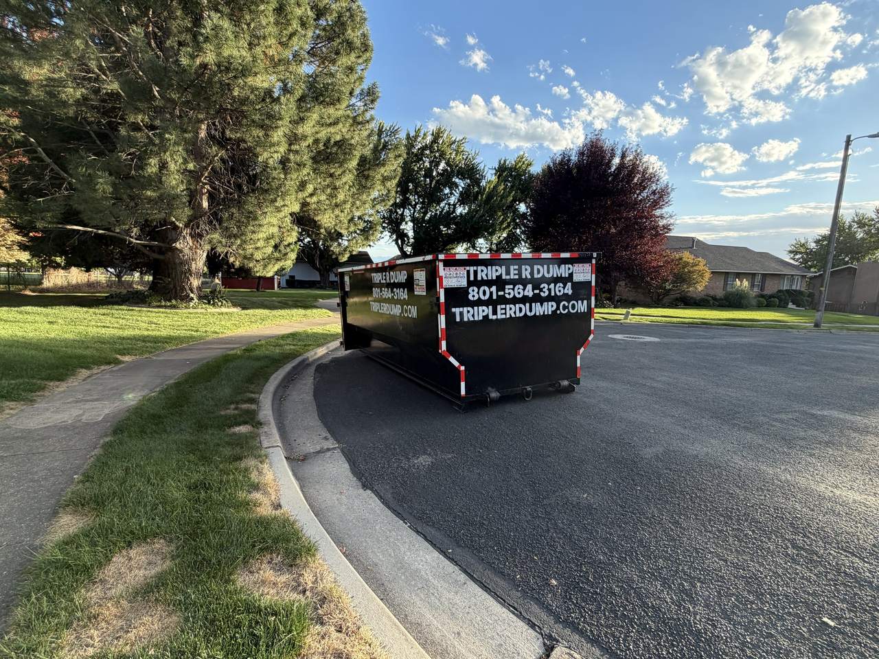 Triple R Dump roll-off dumpster at the curb on a curved street in North Ogden, Utah
