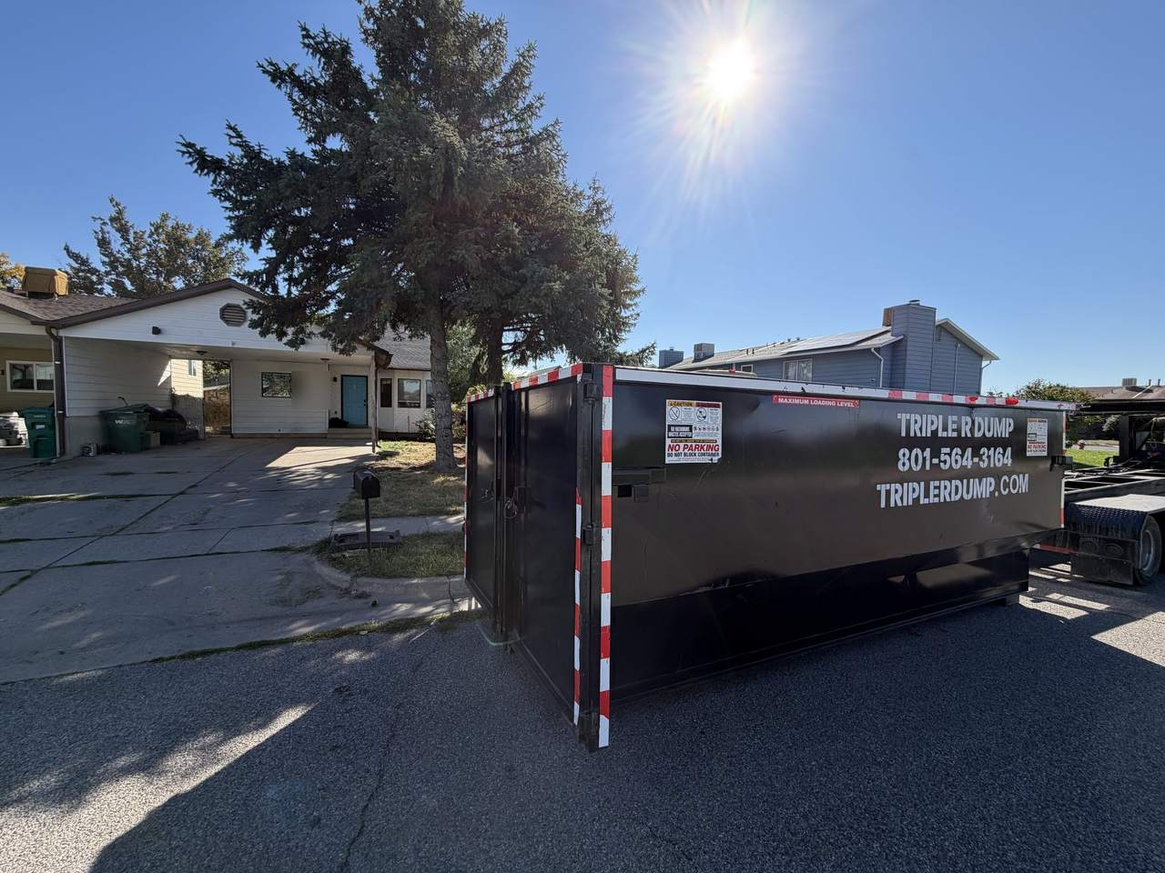Triple R Dump roll-off dumpster parked on a residential street in Roy, Utah