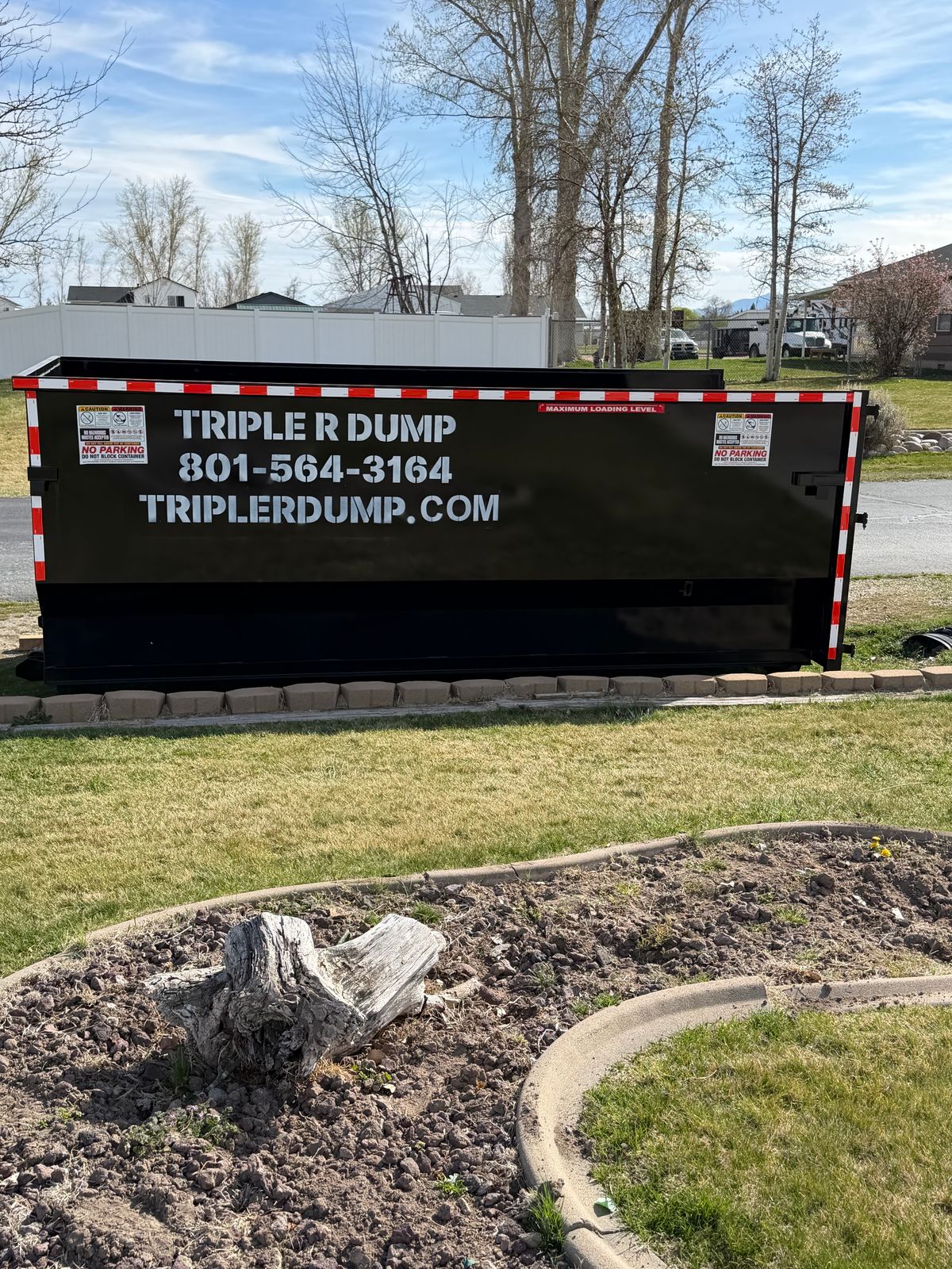 Triple R Dump dumpster set on a curb strip, clear of the landscaping