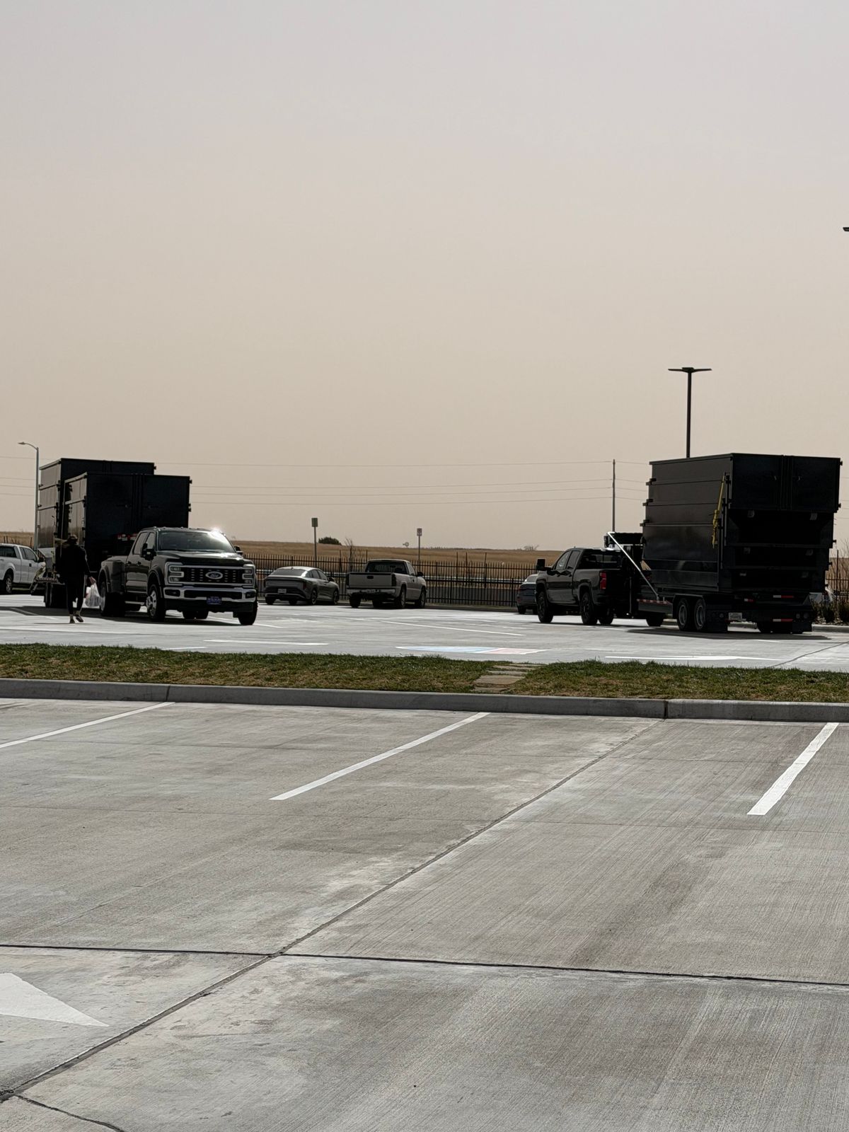 Two Triple R Dump trucks with roll-off bins on a paved lot